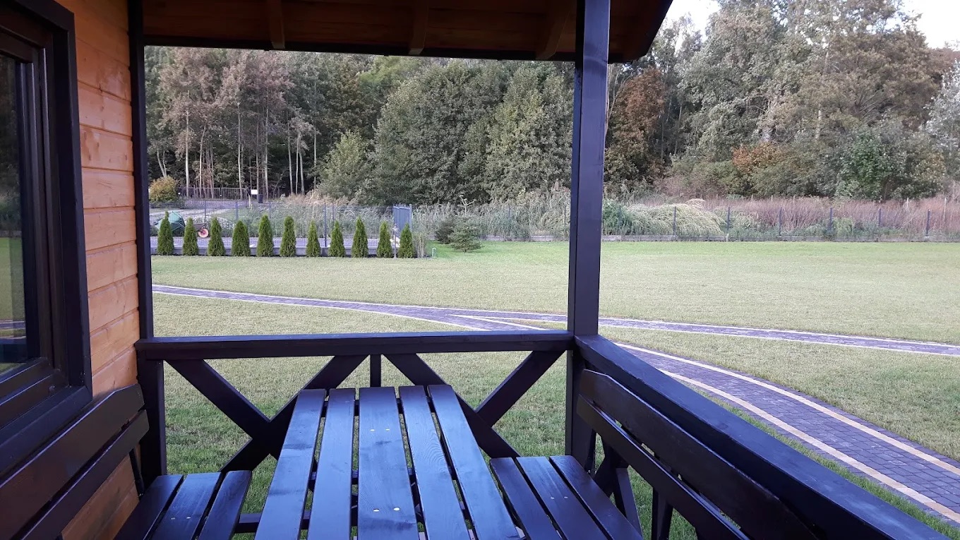 Widok z zadaszonego tarasu domku na zieleń i pobliski las